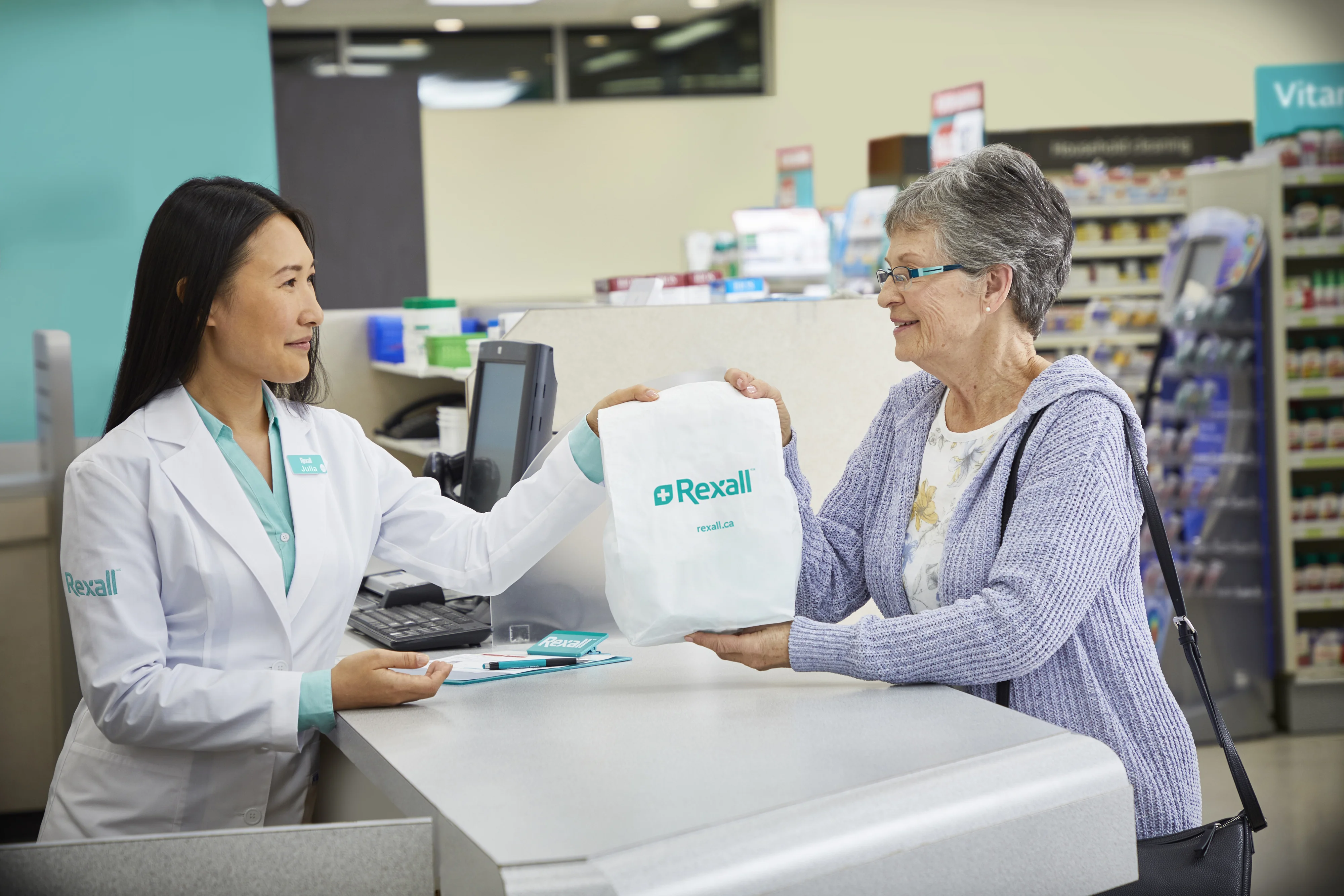 Pharmacist handing a prescription bag to a customer