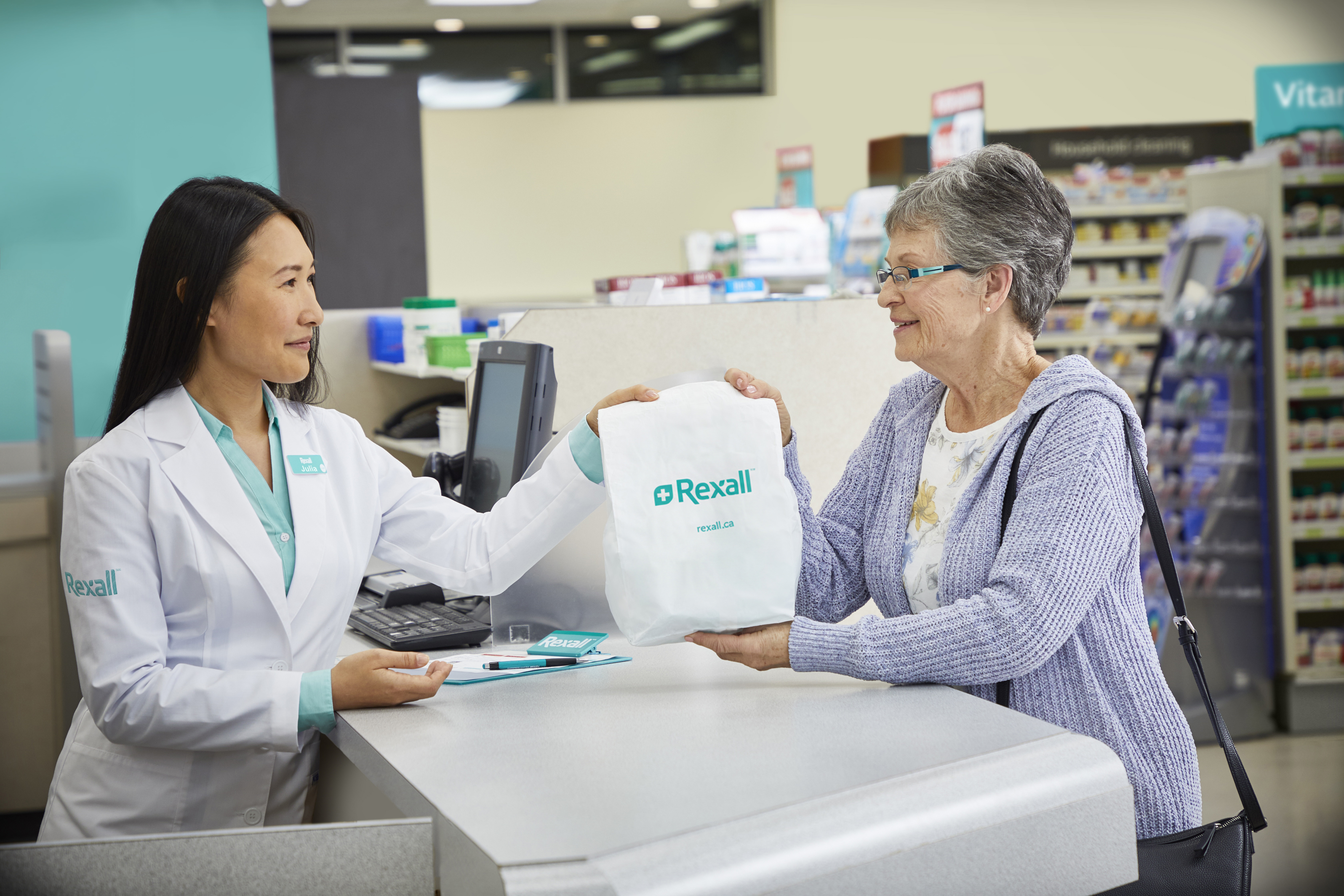 Pharmacist handing a prescription bag to a customer